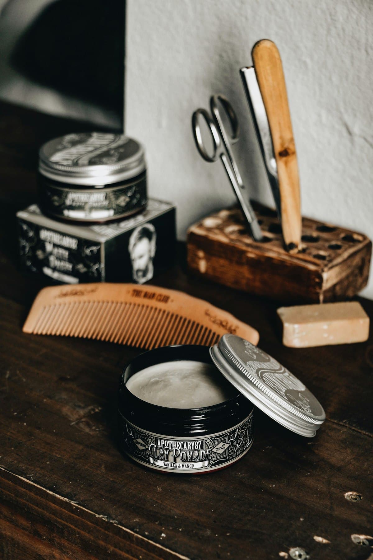 Herramientas de barbería sobre madera: navaja, peine y tijeras